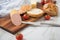 German fine veal liver sausage spread on crispy bread roll bun, with butter, tomatoes, wooden board, kitchen towel and light