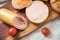 German fine veal liver sausage spread on crispy bread roll bun, with butter, tomatoes, wooden board, kitchen towel and light