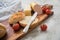 German fine veal liver sausage spread with two crispy bread rolls buns, tomatoes, butter and knife on wooden board, kitchen towel