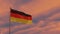 German flag in the wind against the backdrop of a dramatic sunset sky