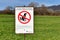 German ``Food is produced on this meadow`-sign with pooping dog in crossed out red circle. Don`t let dogs poop on meadows