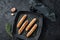 German grilled Bratwurst sausages in a grill pan. Black background. Top view