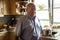 German old man standing in kitchen room waiting lunch in house