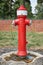 German red fire hydrant in a park with two hose connectors and DIN 80 written on it