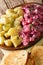 German red herring salad served with boiled potatoes closeup in a plate. vertical
