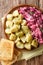 German red herring salad served with boiled potatoes closeup in a plate. Vertical top view