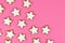 German star shaped glazed cinnamon Christmas cookies called `Zimtsterne` on pink background
