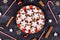 German star shaped glazed cinnamon Christmas cookies called `Zimtsterne` on striped plate surrounded by cinnammon sticks