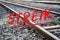 German text Streik meaning strike over rusty metal railway tracks and brackets in a ballast bed, selected focus