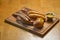 German Thuringer sausage or bratwurst, with baked potatoes and spicy sauce. Served on a rustic wooden board.