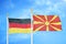 Germany and North Macedonia two flags on flagpoles and blue cloudy sky