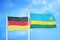 Germany and Rwanda two flags on flagpoles and blue cloudy sky