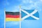 Germany and Scotland two flags on flagpoles and blue cloudy sky