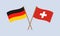 Germany and Switzerland crossed flags on stick. German and Swiss national symbols. Vector illustration