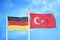 Germany and Turkey two flags on flagpoles and blue cloudy sky