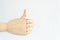 Gesture thumb up, made by artificial wooden hand on white background