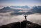 Gesture of triumph. Happy hiker in black. Tall man on the peak of sandstone rock in national park Saxony Switzerland above valley