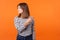 Get out! Portrait of resentful woman with brown hair in long sleeve shirt. indoor studio shot isolated on orange background