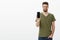 Get yourself awesome gadget now. Pleased confident good-looking charismatic bearded male in t-shirt showing screen of