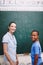 He gets better everyday. A caring teacher standing at the blackboard with her student doing sums.