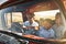 Getting on the road. a cheerful young family driving in a red pickup truck on a rural road outside.