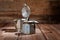 A geyser type metal coffee maker, photographed against a vintage wooden background with coffee beans