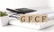 GFCF written on a wooden cube on keyboard with office tools