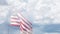 Ghosted slow motion American flag waving in wind with time-lapse clouds