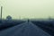 A ghostly blurred man standing in the middle of the road on an eerie misty morning. With a dark, moody colour edit