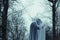 A ghostly hooded figure standing in a forest in winter