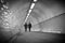 Ghostly people walk through an underground tiled tunnel. Black and white