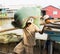 An Giang, Vietnam - Nov 29, 2014: Worker carries heavy bag of fish food from small wooden transportation boat to floating fish far