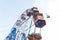 Giant ferris wheel with colorful empty booths. Bottom view of a ferris wheel and blue sky on a sunny summer day.