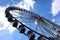 Giant ferris wheel detail. white gondolas. blue sky.