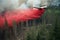 A giant firefighting air tanker plane flying low and releasing a massive deluge of fire retardant chemicals onto the burning