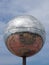 A giant glitter ball on blackpool promenade with blue sky and reflection of the town in the mirrored surface