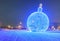 Giant glowing blue Christmas ball on the street with snow