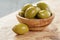 Giant green olives in olive bowl on wood