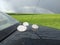 Giant hailstones displayed on a black car after a powerful storm has passed
