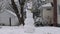 Giant odd snowman in front yard with slow falling snow