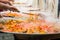 The giant paella. Stirring of cooking ingredients in large frying pans.