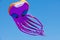 Giant purple octopus kite, 100 feet long, in the air, against pure blue sky
