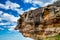 Giant rock suspended above the ocean with blue sky on background