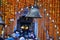 Giant rustic bell surrounded by marigold flower curtains in front of the Kedarnath Temple entrance