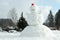 A giant snowman with a red bucket as a hat in Northern European garden