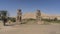 Giant statues of the colossi of Memnon against the blue sky and sand dune.