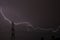 A giant thunderstorm flashes through a high voltage pylon and touches the roofs of the surrounding houses