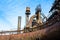 Giant tubes and stacks as part of a derelict industrial structure, rusted metal and smoke stacks, blue sky copy space