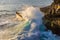 Giant wave crashing against rocky outcrop, Devils Tear, Nusa Lembongan, Bali. Tide pool behind; ocean in background.