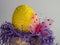 Giant yellow beaded Easter egg in a basket with purple paper shreds spilling out and a pink mesh butterfly with pink gemstones and